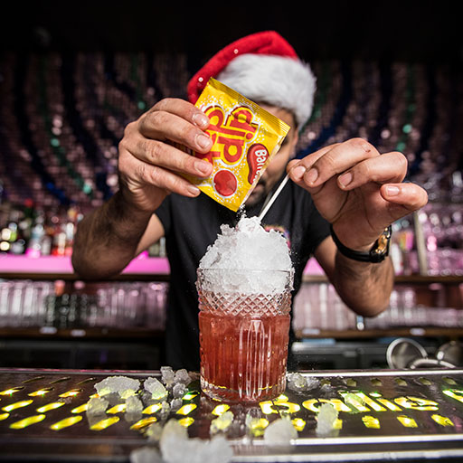 a man in a santa hat making a christmas cocktail