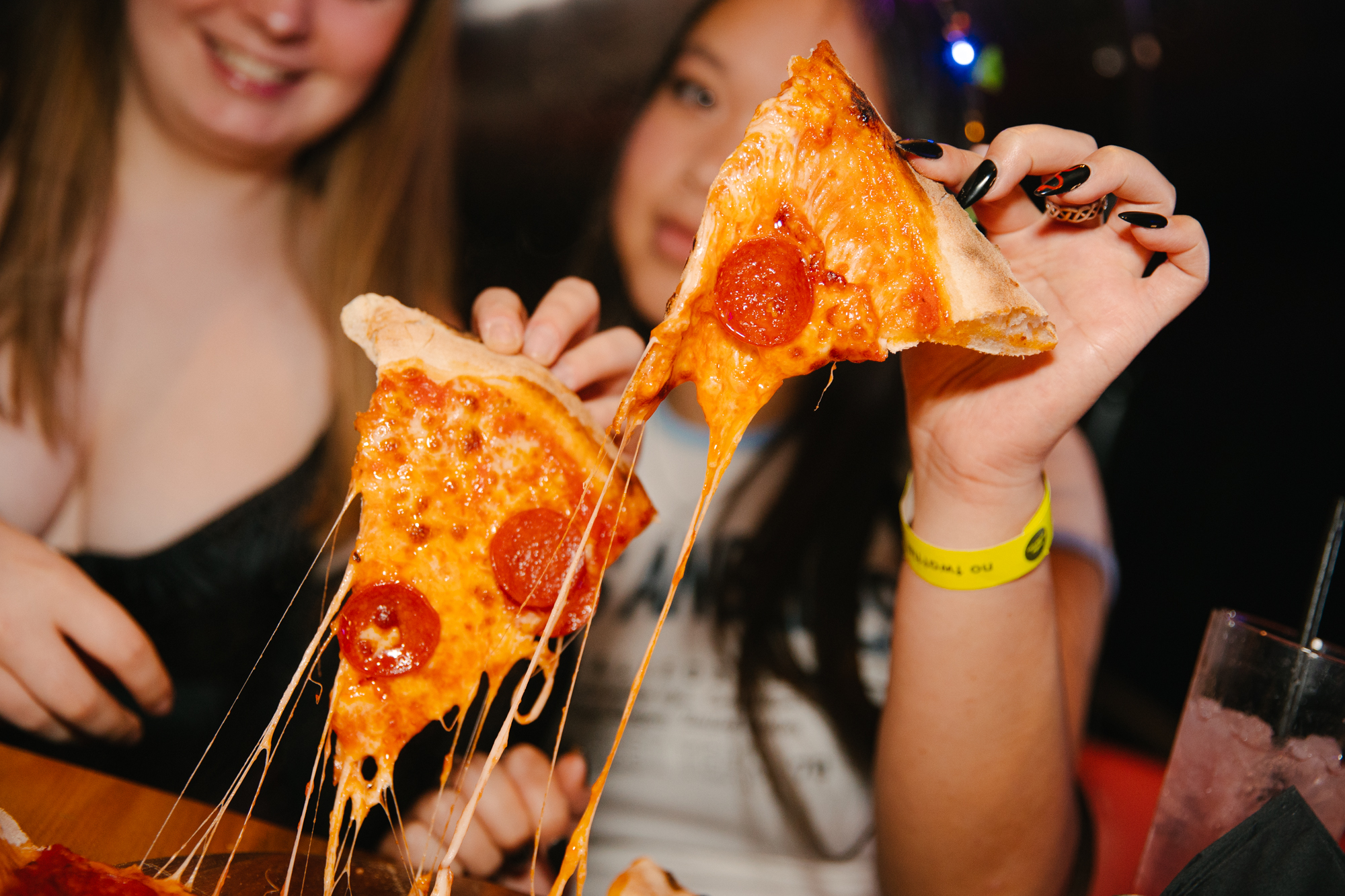 two girls eating pizza at a bottomless brunch