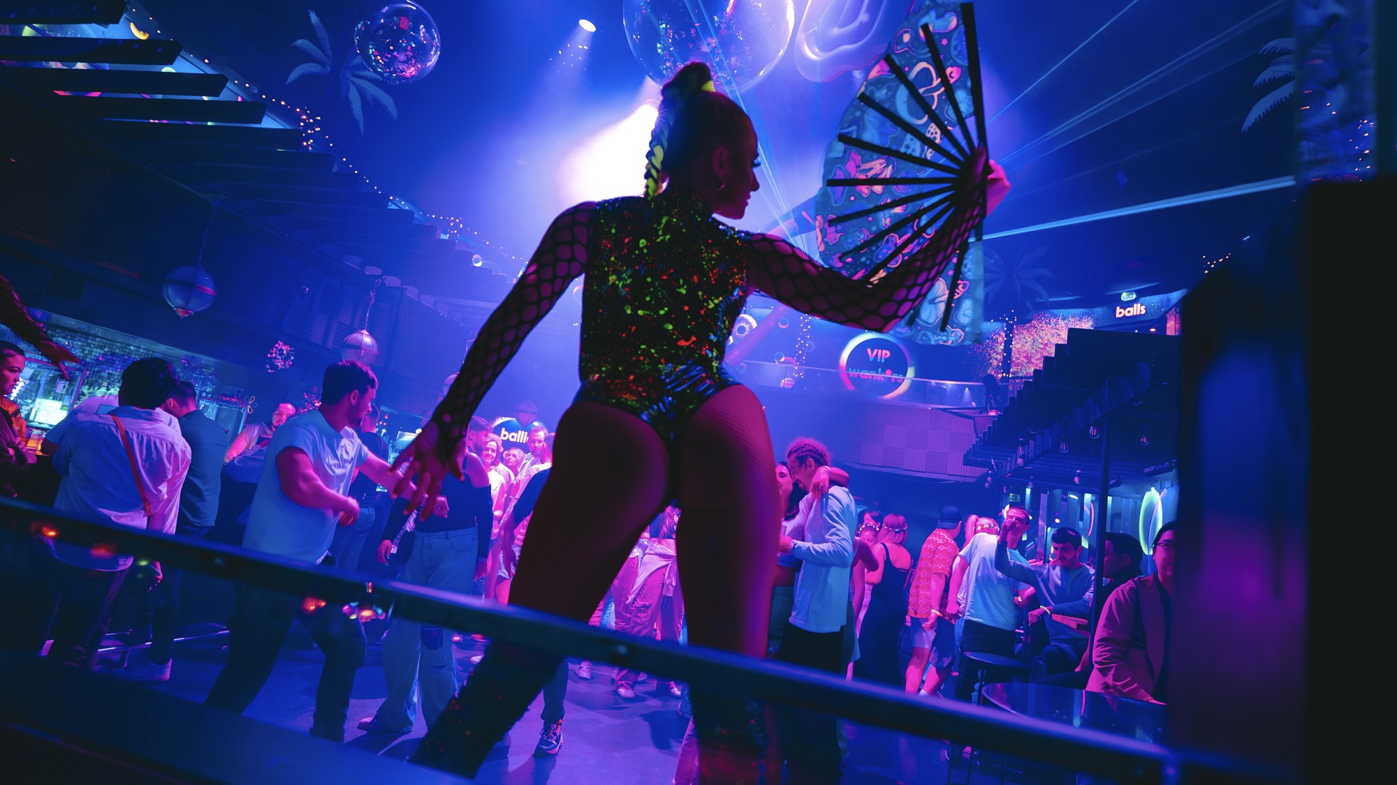 a dancer with a big fan stood on a podium, dancing for a crowd