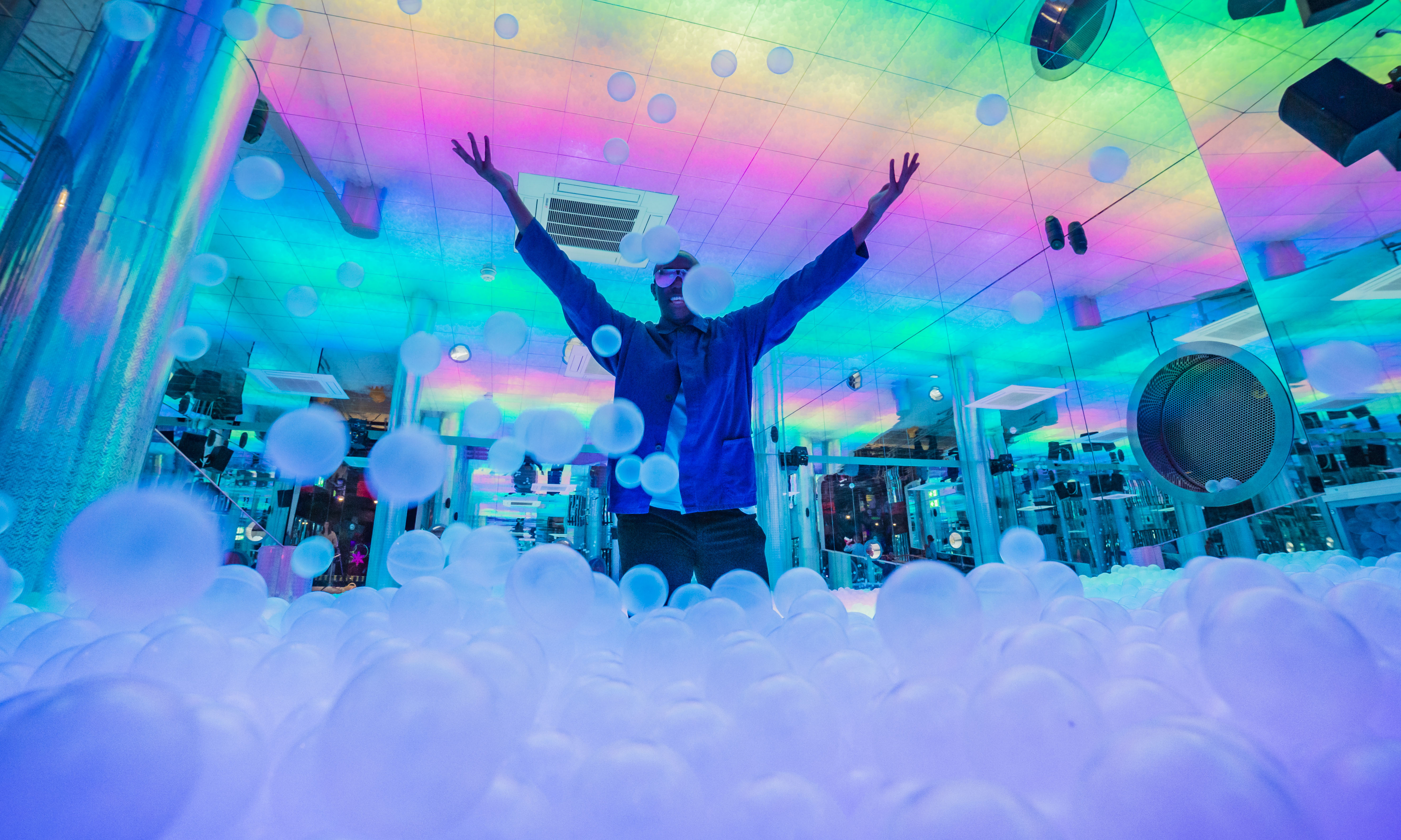 a man throwing balls in a multicoloured ball pit