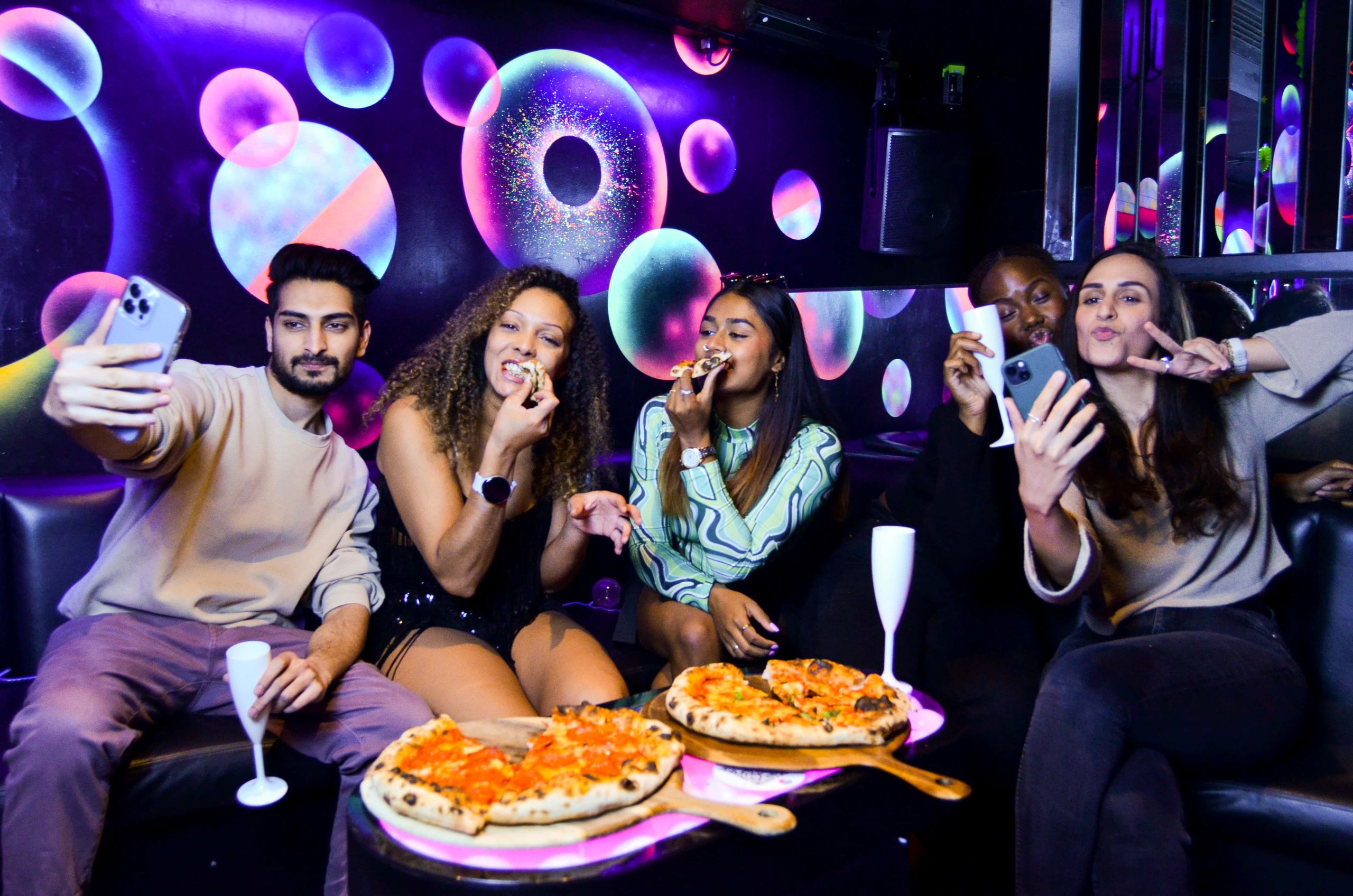 a group of friends eating pizza and drinking prosecco taking a selfie